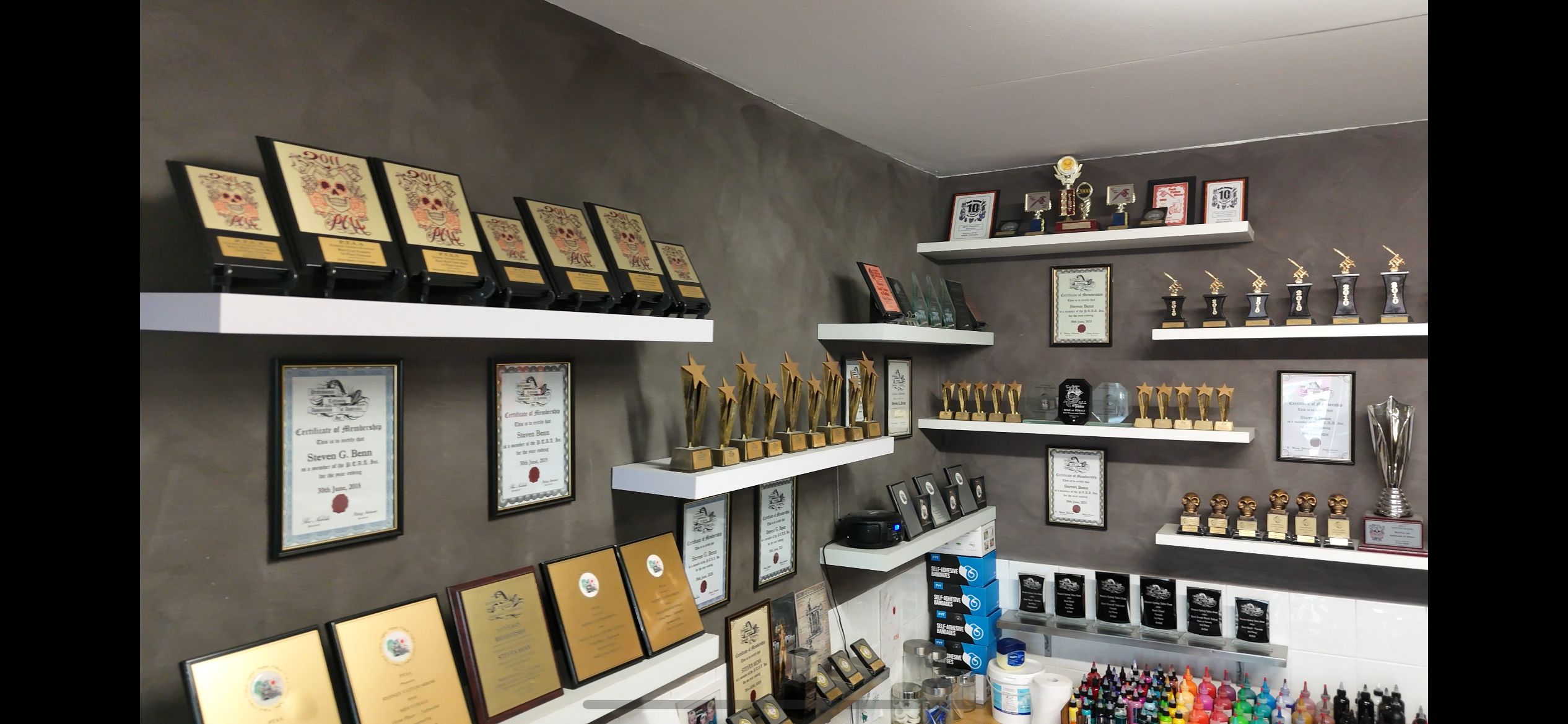 Diamond Tip Tattoo awards wall with trophies and certificates